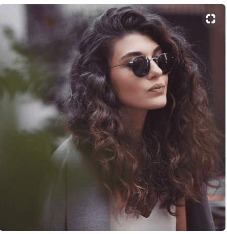 Beautiful woman with brunette curly hair and sunglasses.