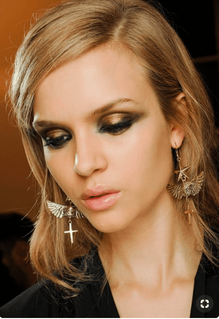 Glamorous blonde woman wears smoky metallic eye makeup.